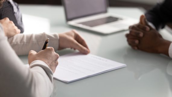 Close,Up,Diverse,Hands,Sign,Up,Document,At,Meeting.,Client